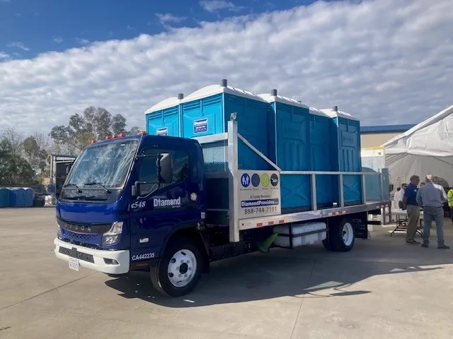 Diamond Environmental Services RIZON electric flatbed truck carrying portable restrooms