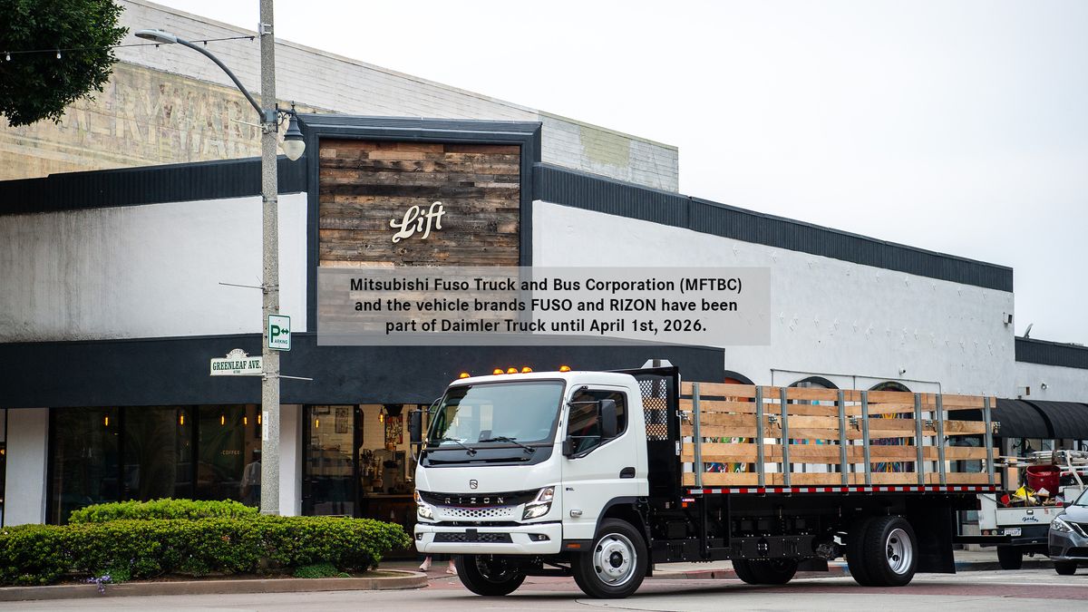 White RIZON electric stake-bed truck parked on a street in front of a commercial building